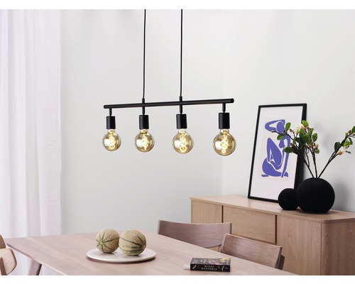 Svart hänglampa med fyra lampor ovanför ett matbord