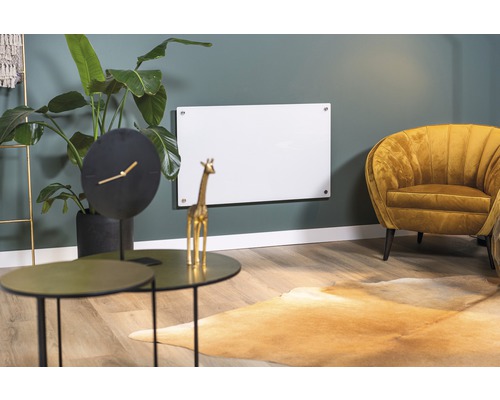 Vardagsrum med infraröd värmare på väggen, bord, klocka och fåtölj