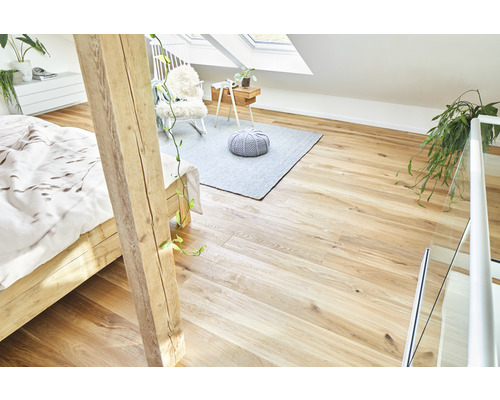 Ljust vindsrum med trägolv, säng, matta och sittmöbler