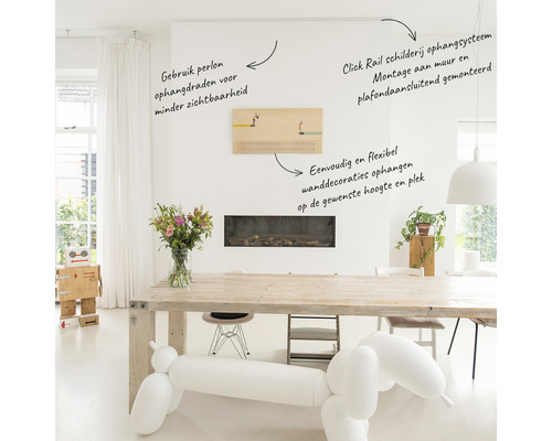 Ljust vardagsrum med ett målningsgallerisystem monterat på väggen och taket, med upphängningskablar i perlon och ett flexibelt sätt att fästa väggdekorationer på höjden.