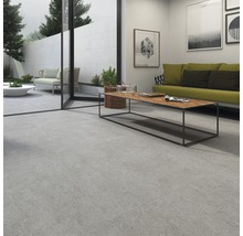 Inomhus- och utomhusutrymme med stora plattor, altandörr, soffa, bord och dekoration