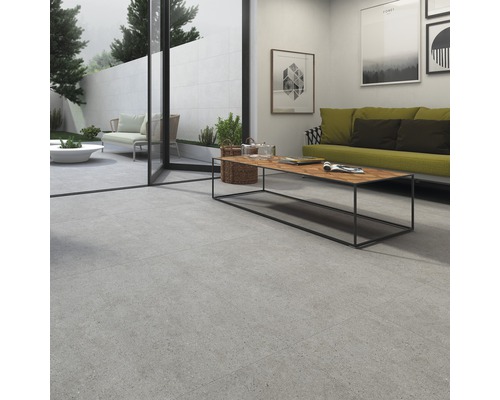 Inomhus- och utomhusutrymme med stora plattor, altandörr, soffa, bord och dekoration