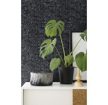 Dekorativ väggdesign med mosaikplattor i ett rum med krukväxter och dekorativa element.