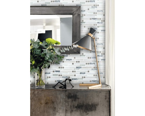 Väggdekoration med mosaikplattor i modern stil med spegel och lampa på ett skåp.