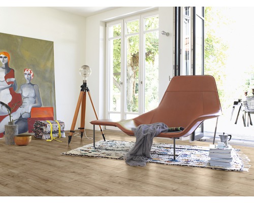 Ljust rum med trägolv, fåtölj, lampa och målning