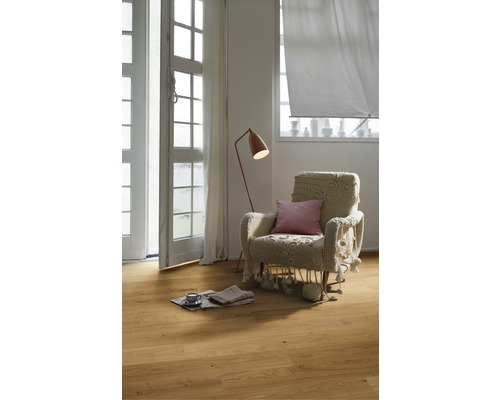 Ljust rum med trägolv, fåtölj, golvlampa och fönster