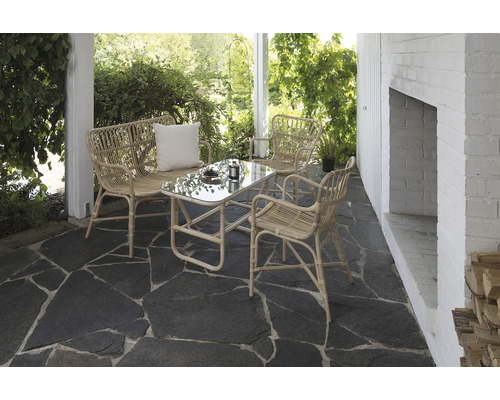 Uteplats med rottinggrupp och glasbord på stengolv