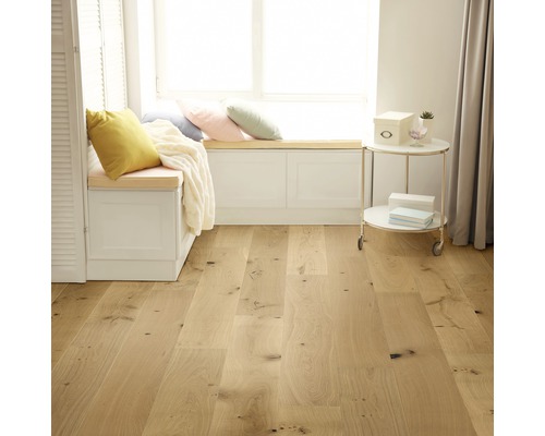 Ljust rum med trägolv, fönsterbänk med kuddar och sidobord