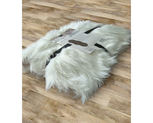 Vit fuskpälsmatta, rullad och märkt på trägolv