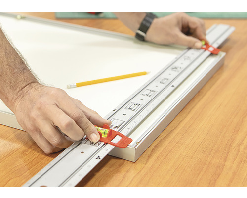 Hantverkare använder en mätsticka med vattenpass för att rikta in en fotoram.