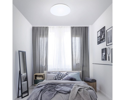 Sovrum med säng, gardiner och rund taklampa