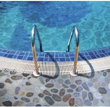 Poolstege i metall med stentrappa till poolen