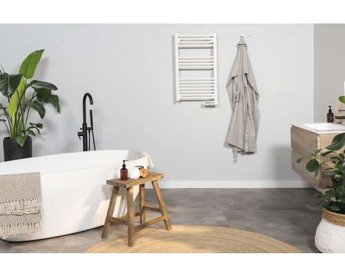 Modernt badrum med badkar, tvättställ, handdukstork och dekorationer.