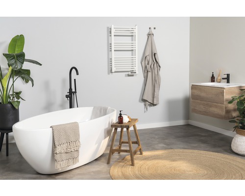 Ljust badrum med badkar, tvättställ, handdukstork och dekorationer för en vänlig atmosfär.