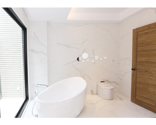 Ljust badrum med fristående badkar, toalett och trädörr