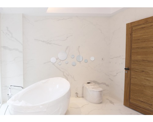 Modernt badrum med fristående badkar, toalett och runda speglar som dekoration