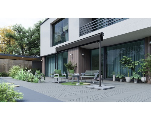 Uteplats med möbler, markis och växter framför ett hus