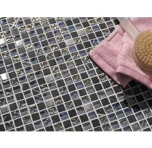 Mosaikplattor av glas och natursten med handduk och borste