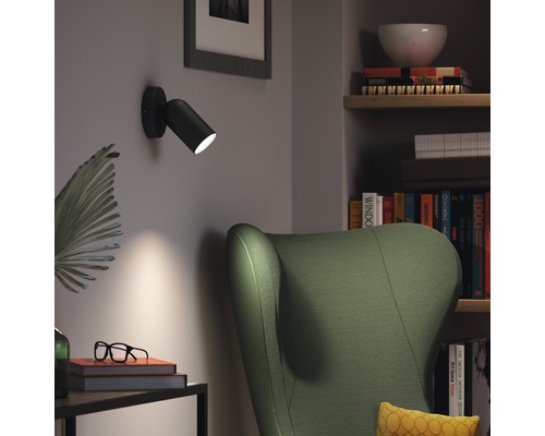 Vardagsrum med fåtölj, bokhylla och svart vägglampa