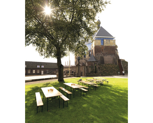 Ölträdgårdsscen med träbord och bänkar på en gräsmatta framför en slottsbyggnad