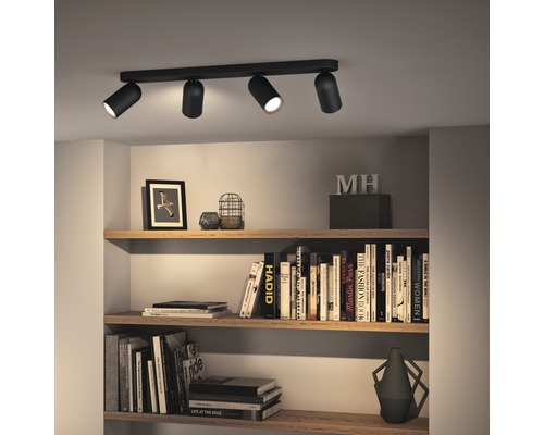Taklampa med fyra spotlights ovanför en bokhylla.