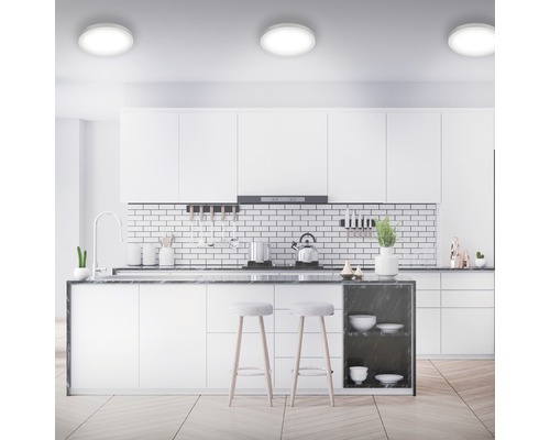 Modernt kök med vita skåp, köksö, barstolar och taklampor