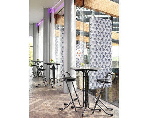 Ståbord med barstolar i ett ljust rum med stora fönster.