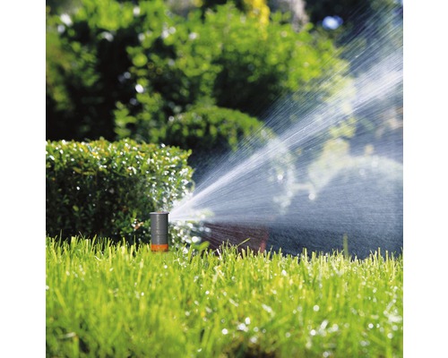 Grässpridare vattnar gräsmattan i trädgården.