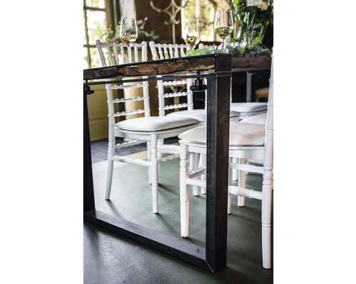 Närbild av ett matbord med metallram och träskiva, omgivet av vita stolar.