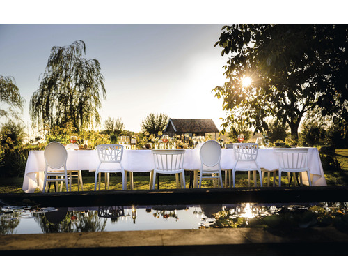 Festligt dukat matbord med vita stolar i trädgården