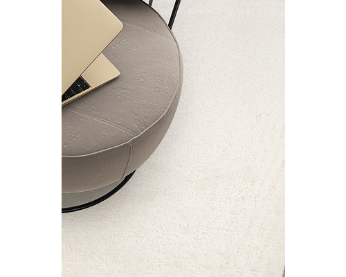 Detaljvy av en ljus matta bredvid ett sidobord med bärbar dator