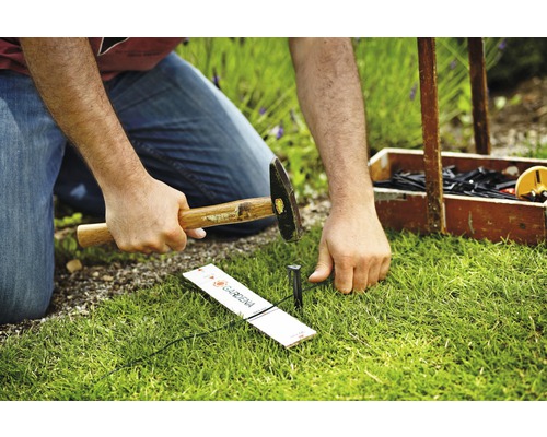 En person hamrar en Gardena Micro-Drip-systemrörhållare i gräsmattan