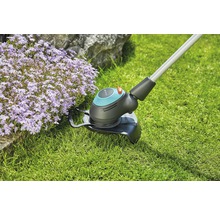 Grästrimmer i drift bredvid blomsterrabatt