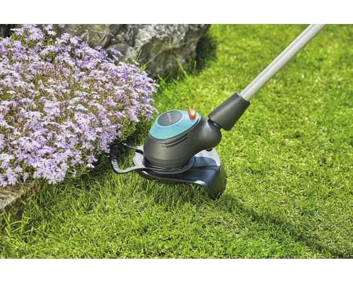 Grästrimmer i drift bredvid blomsterrabatt