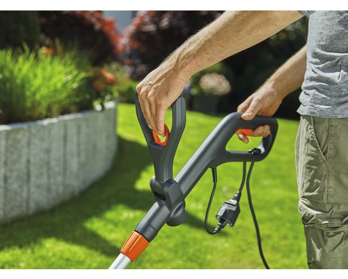 Närbild av en person som använder en grästrimmer med sladd