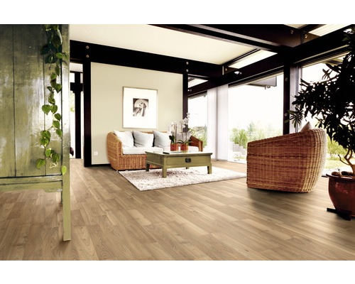 Ljust vardagsrum med trägolv, rottingfåtölj och träbord på matta