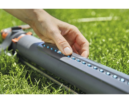 En person justerar munstyckena på en vattenspridare.