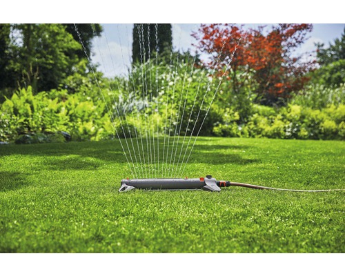 Grässpridare i bruk på en grön gräsmatta