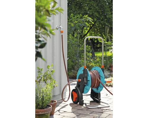 Trädgårdsscen med en trädgårdsslangvagn med slanganslutning till en vattenkran