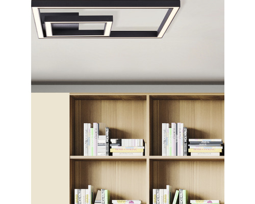 Modern taklampa i metall med geometrisk design ovanför en bokhylla