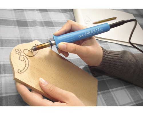 Person som arbetar med en pyrografipenna på en träbräda.