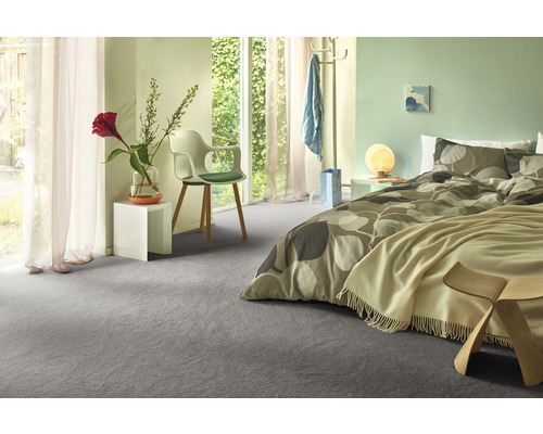 Ljust sovrum med grå heltäckningsmatta, säng och dagsljus