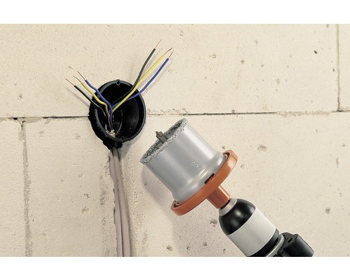 Borrmaskin med hålsåg borrar hål i väggen för elledning