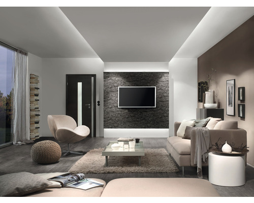 Vardagsrum med soffa, fåtölj, soffbord och TV på en stenmur