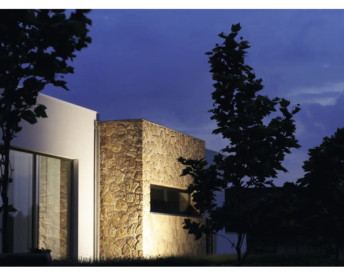 Exteriör av ett modernt hus med stenbeklädnad och fönster på natten