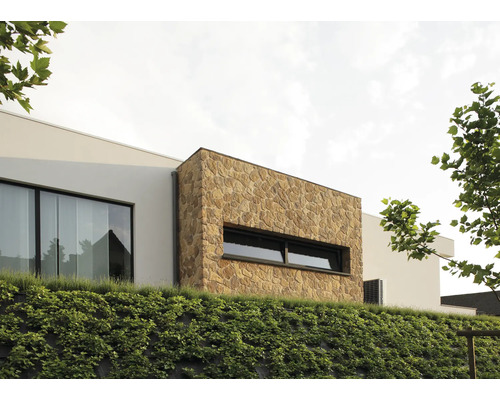 Exteriörvy av ett modernt hus med naturstensfasad och grönskande sluttning