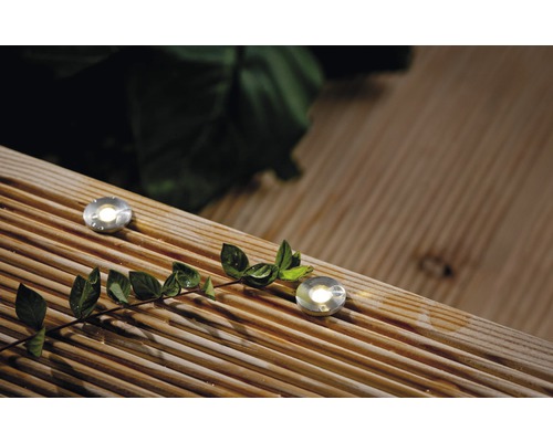 Två infällda metallspotlights på en träterrass