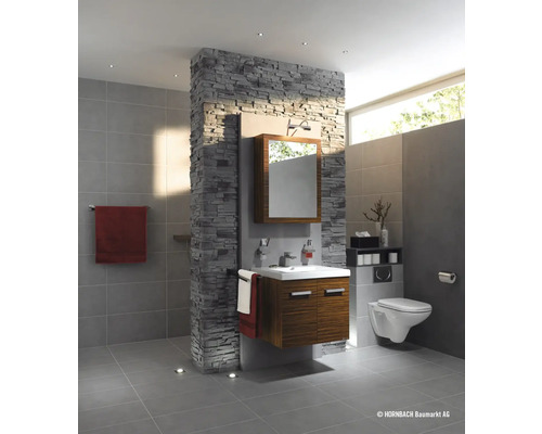 Badrum med tvättställ, spegel, toalett och väggbeklädnad med stenutseende