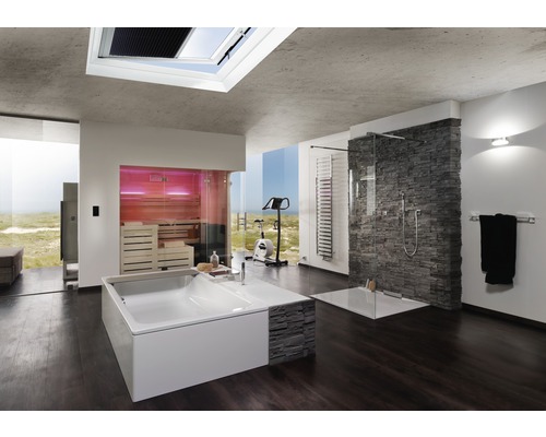 Ljust badrum med badkar, dusch, bastu och träningsmaskin framför ett stort fönster