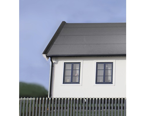 Vy över ett hus med grått tak, vita väggar och ett staket